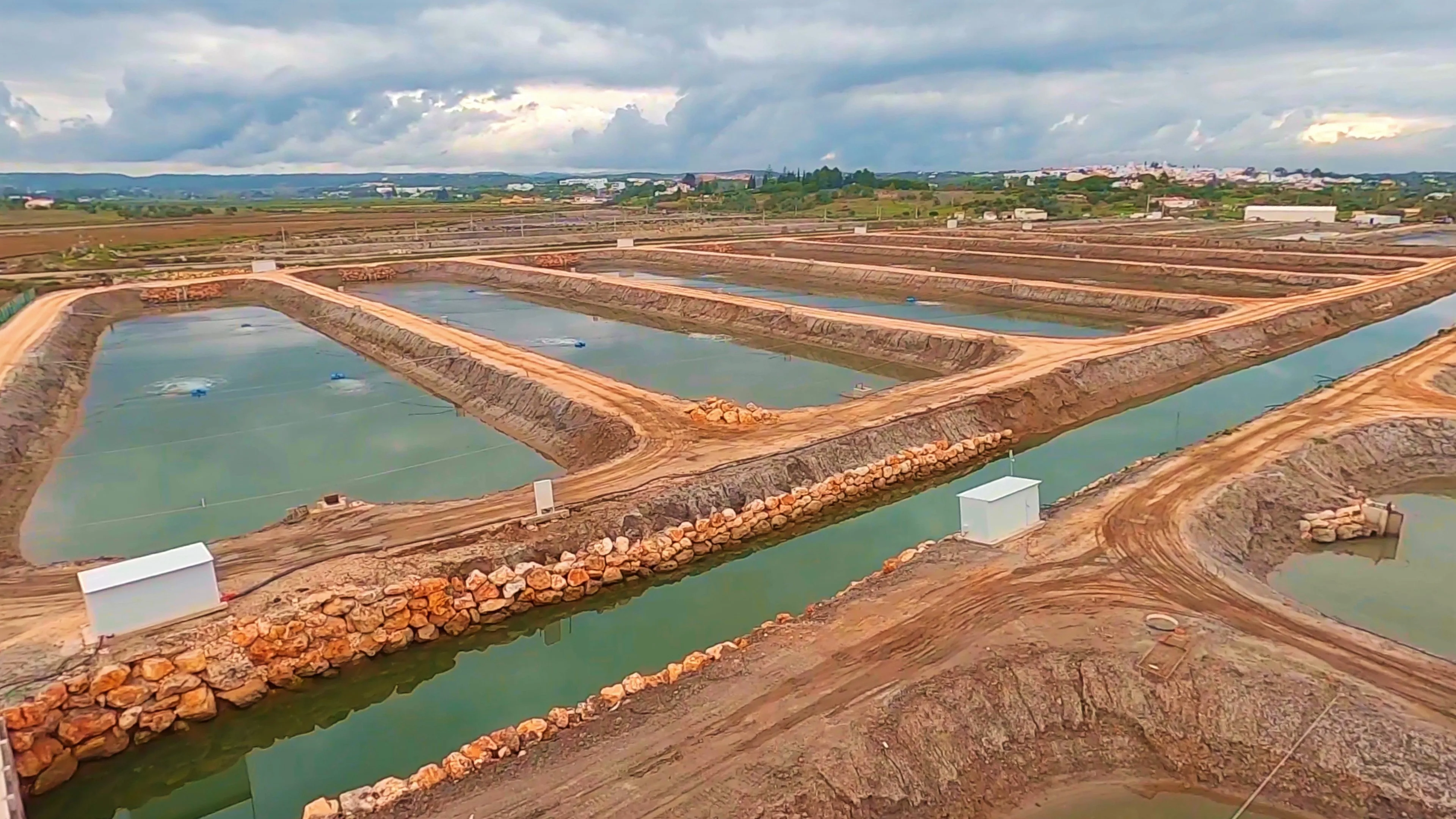 Ground-level view of NaturaFish aquaculture ponds with stone channels in the Algarve